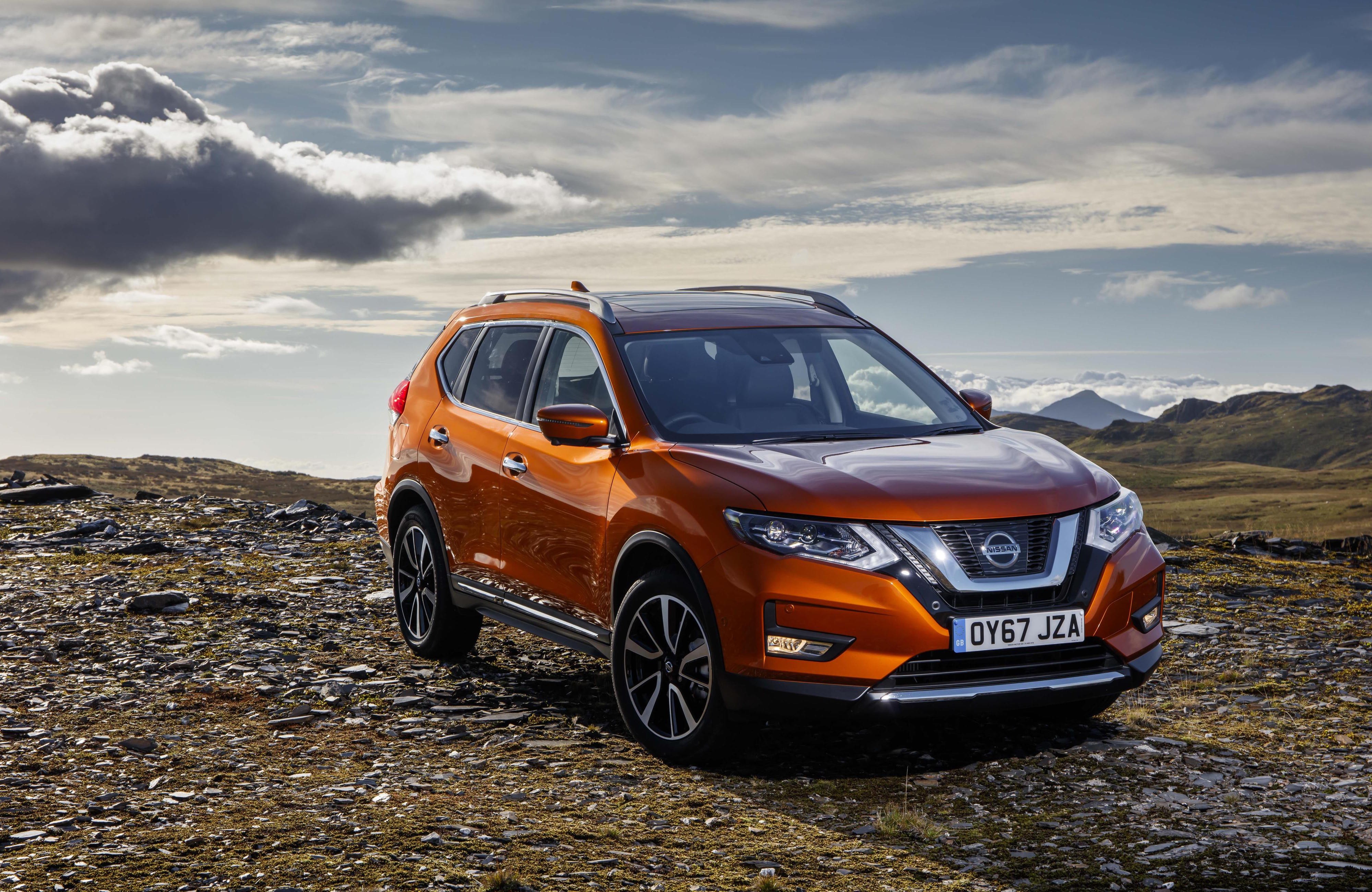Amber Nissan X-Trail parked on a mountain range.